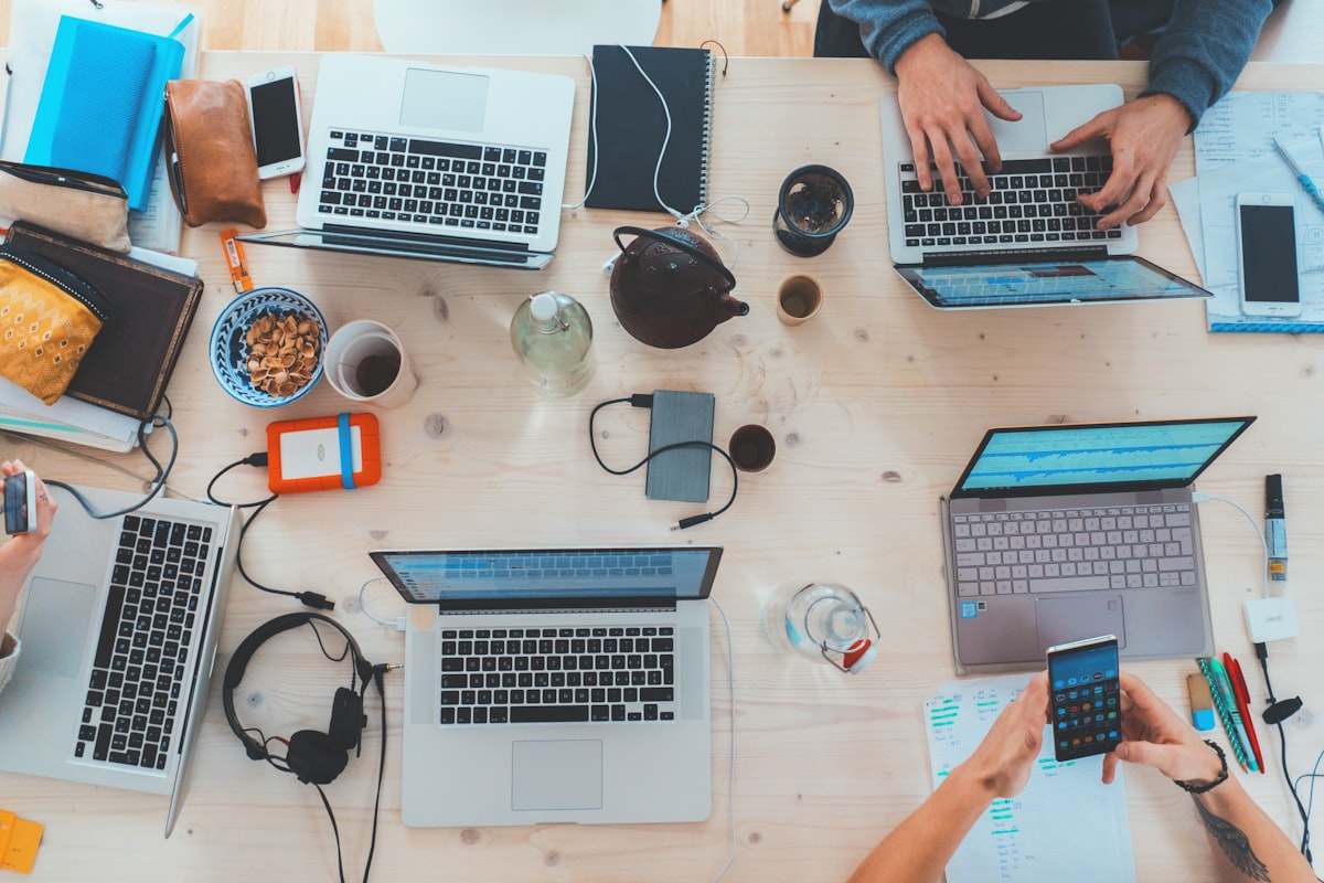 Leads and work scattered across many laptops, phones and notes on a desk
